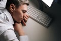 Top view of tired sleepy male employee asleep on computer desk late at night. Exhausted businessman sleeping with head Royalty Free Stock Photo