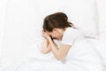 Top view of tired stressed crying young brunette woman lying in bed with white sheet, pillow, blanket. Shocked Royalty Free Stock Photo