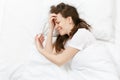 Top view of tired stressed crying young brunette woman lying in bed with white sheet, pillow, blanket. Shocked