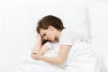 Top view of tired stressed crying young brunette woman lying in bed with white sheet, pillow, blanket. Shocked Royalty Free Stock Photo