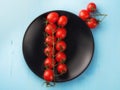 Top of view to the group of cherry fresh tomatoes on the black dish and blue wooden background. Royalty Free Stock Photo
