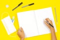 Top view to kid hands writing on open notebook. School supplies, hand sanitizer and medical face mask on yellow Royalty Free Stock Photo