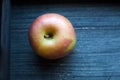 Top view to round red and green ripe cortland apple on grey wooden background. Isolated round fruit. Raw vegetarian food Royalty Free Stock Photo