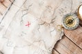 Top view to vintage fake treasure map with red cross and compass on wooden desk Royalty Free Stock Photo