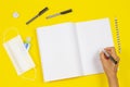 Top view to woman hand writing on open notebook. School supplies, hand sanitizer and medical face mask on yellow Royalty Free Stock Photo