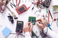 Top view of tools with soldering iron, multimeter, pliers and other equipments on white wooden background, faceless portrait of