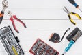 Top view of tools with soldering iron and pliers on white wooden background