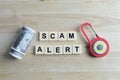 Top view of toy padlock, money banknote and scrabble letters with text SCAM ALERT