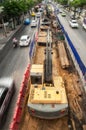 Top view, a tracked excavator on a construction site at traffic island, vehicle moving on an asphalt road Royalty Free Stock Photo