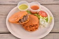 Top view of a traditional Torta ahogada with meat on a plate served with sauces on a wooden table