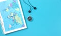 Top view of travel notebook with world map, magnetic compass and headphones on blue background. Space for text Royalty Free Stock Photo