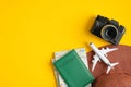 Top view of traveler accessories. Flat lay beach hat, passport, map, airplane, photo camera on yellow background with copy space.