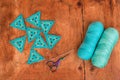 Top view of triangle crochet patterns, two skeins of yarn, a hook and scissors on brown wood background. Royalty Free Stock Photo