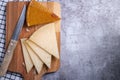 Top view of triangle pieces of cured Manchego cheese and a sharp knife on a wooden food board