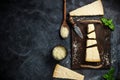 Top view of triangular piece of hard cheese on wooden cutting board