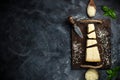 Top view of triangular piece of hard cheese on wooden cutting board