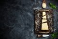 Top view of triangular piece of hard cheese on wooden cutting board