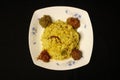 Top view of turmeric rice with meatballs in a white plate isolated on a black background Royalty Free Stock Photo