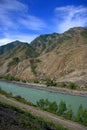 Top view of the turquoise river flowing through a hilly valley and a dirt road running along the coast Royalty Free Stock Photo