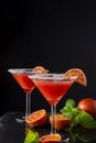 Top view of two blood orange martini glasses, half orange and mint, on black background, vertical Royalty Free Stock Photo