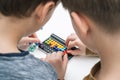 Top view of two boys friends playing colorful 3D puzzle classic pyramid game, putting beads in order on black board. Royalty Free Stock Photo