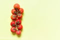 Branch of tomatoes on light yellow background.