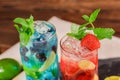 Top view of two bright alcoholic cocktails with mint, lime, ice, strawberries on the wooden background. Summer beverages. Royalty Free Stock Photo