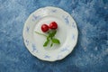 Top view of two cherries on a blue and white porcelain plate. Blue background