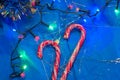 Top view of two Christmas candies with the colorful garland on the bright blue paper