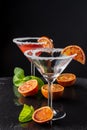 Top view of two cocktail glasses with Blood Orange Martini, one empty, with selective focus, with half orange and mint, on black b Royalty Free Stock Photo