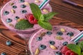 Top view of two colorful smoothie cocktails on a wooden background. Refreshing beverage with ripe bright berries, seeds and mint l Royalty Free Stock Photo