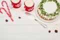 Top view of two cups of cocoa with marshmallows and christmas pie with icing on white wooden table.