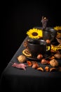 Top view of two cups of tea on table with black tablecloth, nuts, yellow flowers and dark lit candle, black background Royalty Free Stock Photo