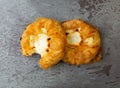 Top view of two delicious cream cheese danishes with one missing a bite on a gray mottled tabletop