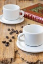 Top view of two empty white coffee cups, on rustic wooden table with coffee beans and book, selective focus Royalty Free Stock Photo