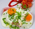 Top view on two fried eggs sunny side yellow runny yolk up on brad with jam, tomatoes and green fresh chives Royalty Free Stock Photo