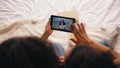 Top view of two girlfriends sitting on bed at home talking on skype on tablet computer with their friend having vacation Royalty Free Stock Photo