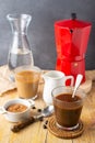 Top view of two glasses with ice coffee, spoon, coffee beans, brown sugar, milk jug with red coffee pot and bottle of water, with Royalty Free Stock Photo