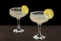 Top view of two glasses of margarita cocktail with lime slices and salt, on wooden table, horizontal black background, Royalty Free Stock Photo