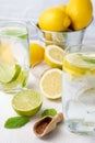 Top view of two glasses of water with half lemons on plate, brown sugar, bucket with lemons and mint leaves, on white table, Royalty Free Stock Photo