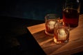 Top view of two glasses of whiskey, rum, brandy or bourbon with ice cube and bottle standing on wooden table over dark Royalty Free Stock Photo