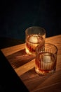 Top view of two glasses of whiskey, rum, brandy or bourbon with ice cube standing on wooden table over dark background. Royalty Free Stock Photo