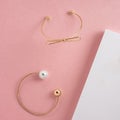 Top view of two modern golden bracelets on pink paper with copy space Royalty Free Stock Photo