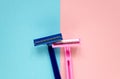 Top view two new disposable razors blue and pink are lying next to each other on blue-pink background Royalty Free Stock Photo