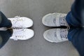 Top view of two pairs of sneakers shoes, legs of loving couple