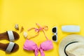 Top view of two pieces pink swimming suit and beach accessoties over yellow background. Royalty Free Stock Photo