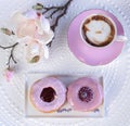 Top view of two pink donuts, a cup of coffee and orchids on a white sur Royalty Free Stock Photo