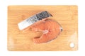 Top view of two portioned salmon steaks on a wooden cutting board over white background.