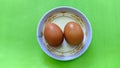 Top view of Two raw brown eggs on a plate isolated on Green background. Eggs are a common ingredient in cooking. Egg protein is a Royalty Free Stock Photo