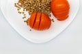 Top view of two red tomatoes and buckwheat, which lie on a white clean plate Royalty Free Stock Photo